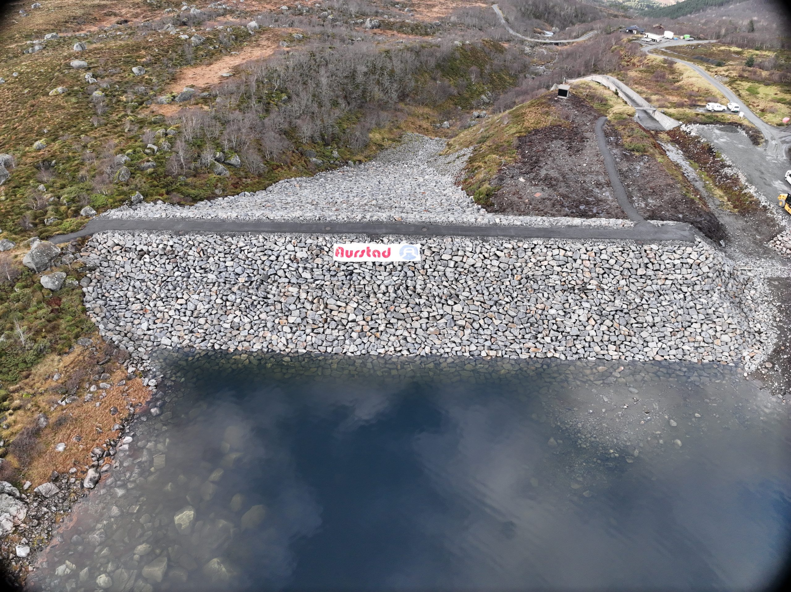 Dronefoto av Dam Børevatn med eit Aurstad-banner.